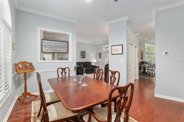 dining room featuring crown molding, baseboards, and wood finished floors