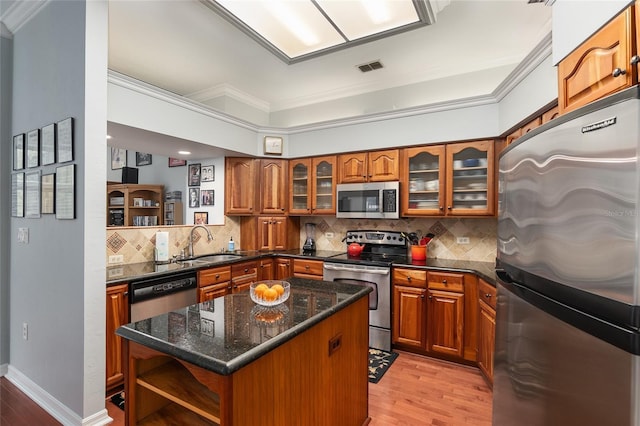 kitchen with stainless steel appliances, open shelves, brown cabinetry, and a sink