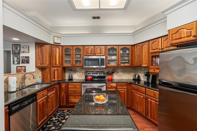 kitchen featuring ornamental molding, appliances with stainless steel finishes, a sink, and brown cabinets