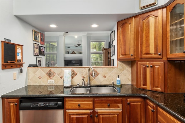 kitchen featuring a fireplace, stainless steel dishwasher, glass insert cabinets, a ceiling fan, and a sink