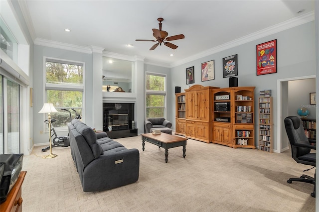 living area with carpet floors, a ceiling fan, baseboards, a glass covered fireplace, and crown molding