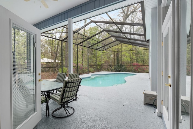 outdoor pool with glass enclosure, ceiling fan, and a patio area