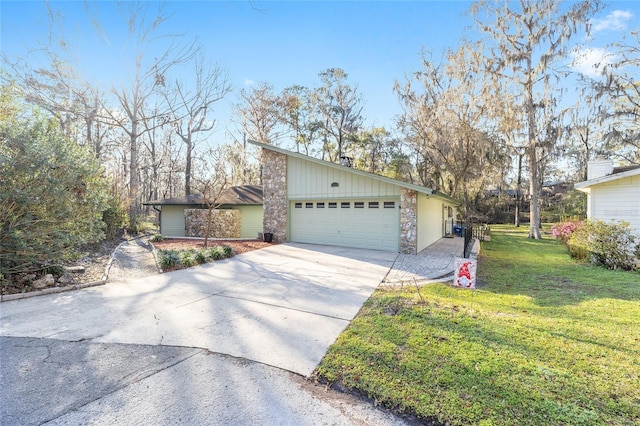 mid-century home featuring a garage, a front yard, stone siding, and driveway