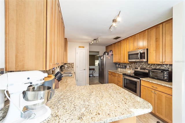 kitchen featuring a toaster, a peninsula, a sink, appliances with stainless steel finishes, and backsplash