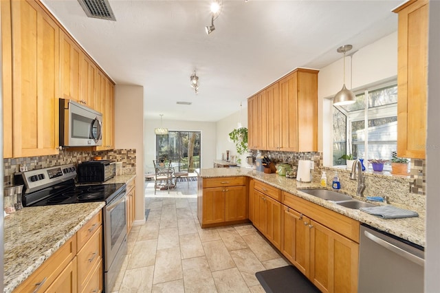 kitchen featuring visible vents, decorative backsplash, hanging light fixtures, stainless steel appliances, and a sink