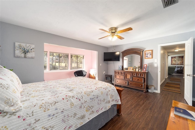 bedroom with a ceiling fan, visible vents, baseboards, and wood finished floors