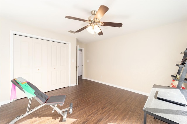 workout room featuring a ceiling fan, visible vents, baseboards, and wood finished floors