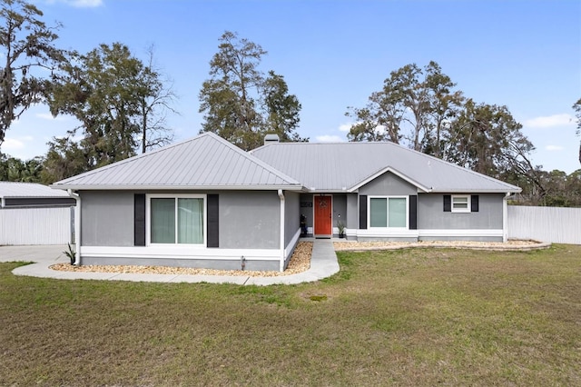 ranch-style home featuring metal roof, a front yard, and fence