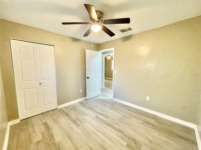 unfurnished bedroom with a closet, visible vents, ceiling fan, wood finished floors, and baseboards