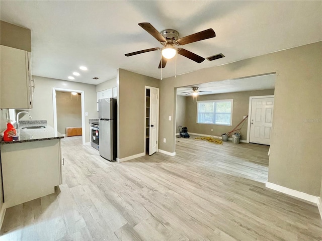 kitchen with light wood-type flooring, a sink, freestanding refrigerator, and baseboards