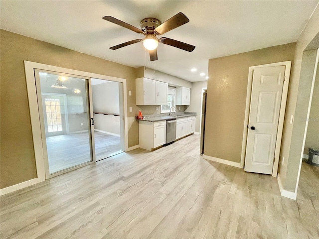 kitchen with baseboards, light wood-style flooring, stainless steel dishwasher, white cabinetry, and a sink