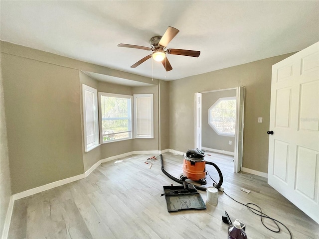 workout room featuring ceiling fan, light wood finished floors, and baseboards