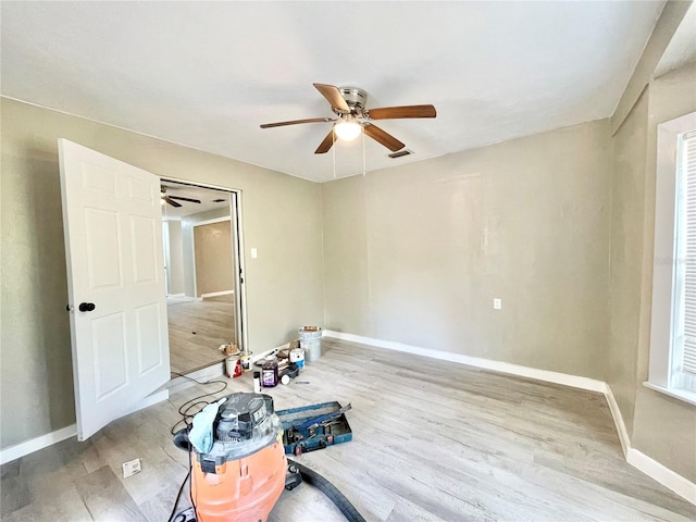 empty room with a ceiling fan, baseboards, visible vents, and wood finished floors