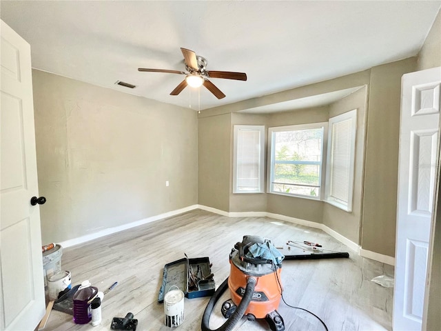 empty room with a ceiling fan, wood finished floors, visible vents, and baseboards