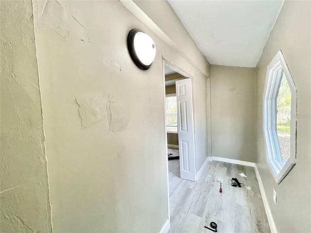 corridor with light wood-style floors and baseboards