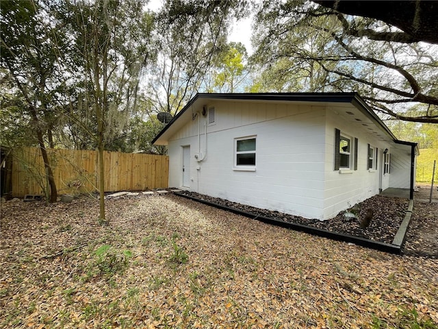 view of property exterior with concrete block siding and fence