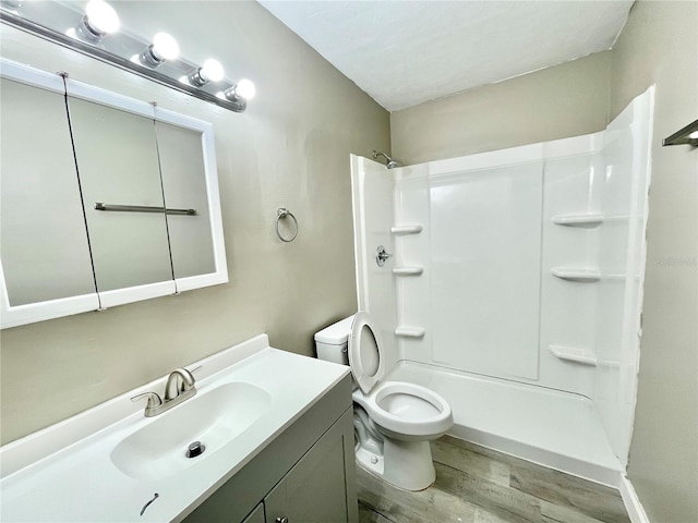 bathroom with a shower, vanity, toilet, and wood finished floors