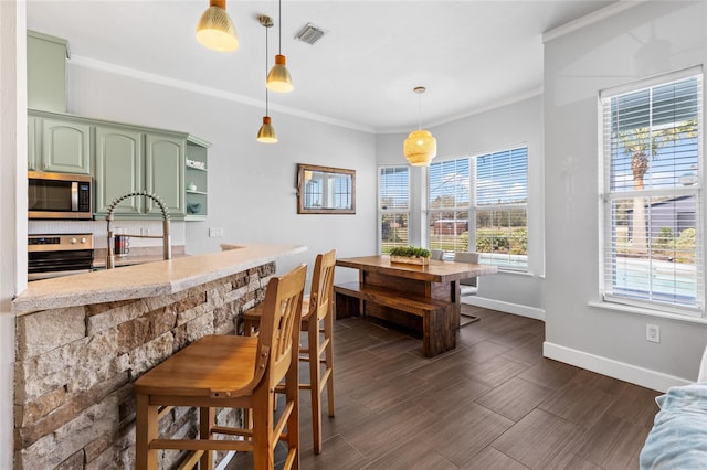 kitchen with stainless steel appliances, visible vents, baseboards, green cabinets, and ornamental molding