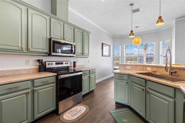 kitchen featuring stainless steel appliances, tasteful backsplash, green cabinets, ornamental molding, and a sink