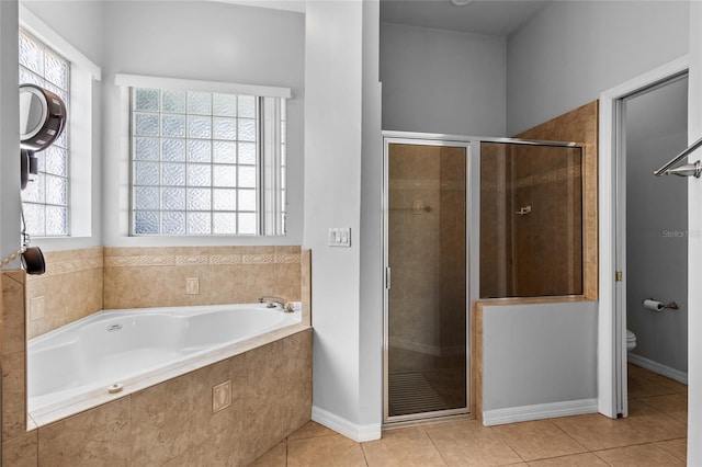 bathroom featuring a garden tub, toilet, baseboards, a shower stall, and tile patterned floors