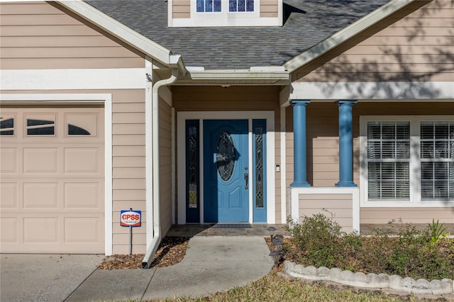 entrance to property featuring a garage and roof with shingles