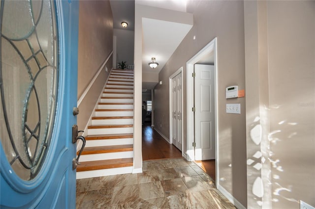 foyer featuring stairs and baseboards