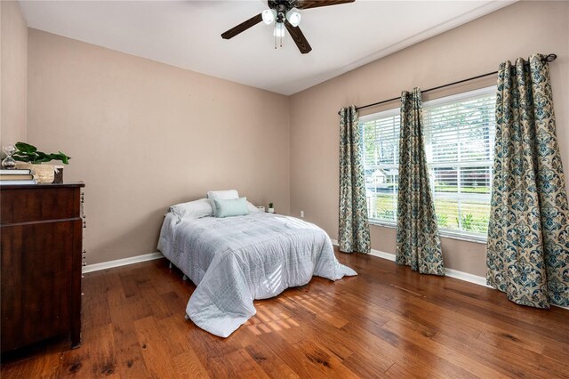 bedroom featuring baseboards, wood finished floors, and a ceiling fan