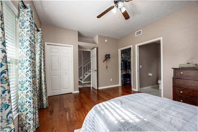 bedroom with wood finished floors, visible vents, baseboards, ceiling fan, and ensuite bathroom