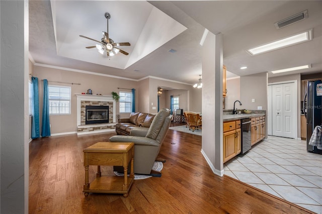 living room featuring a tray ceiling, visible vents, ceiling fan, and light wood finished floors