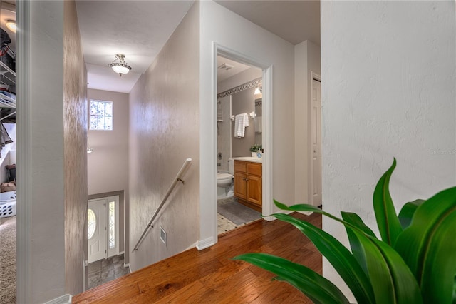 corridor featuring visible vents, an upstairs landing, baseboards, and wood-type flooring