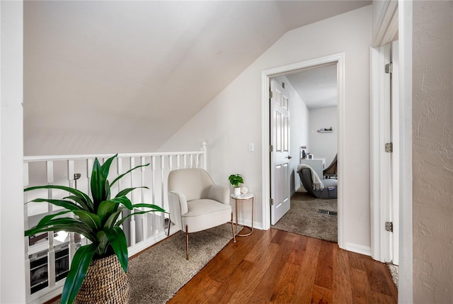 living area with lofted ceiling, wood finished floors, baseboards, and visible vents