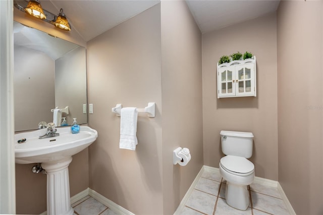 bathroom featuring tile patterned floors, toilet, baseboards, and a sink