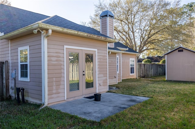 back of house with a shingled roof, fence, a lawn, french doors, and an outdoor structure