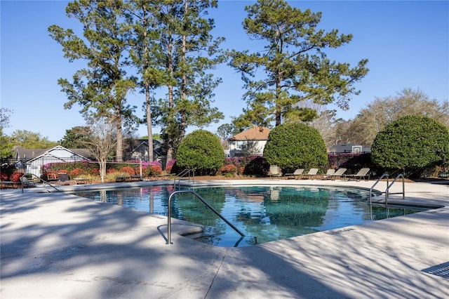 pool with a patio area and fence