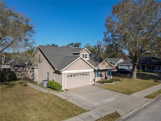 view of front of house with a shingled roof, concrete driveway, central AC, a front yard, and a garage