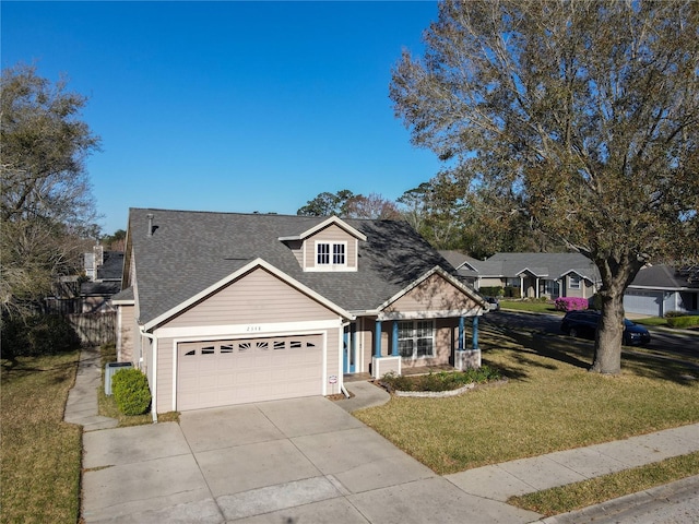 view of front of property featuring a front yard, an attached garage, concrete driveway, and a shingled roof