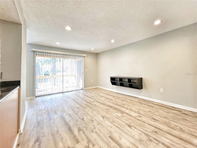 unfurnished living room with light wood-style floors, baseboards, a textured ceiling, and recessed lighting