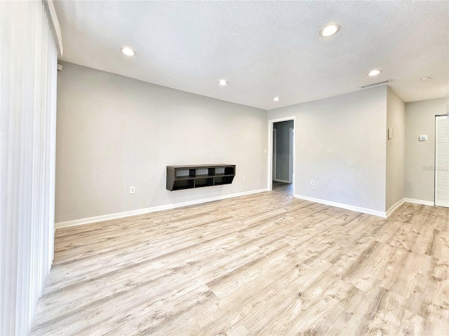 unfurnished living room with recessed lighting, visible vents, light wood-style floors, a textured ceiling, and baseboards