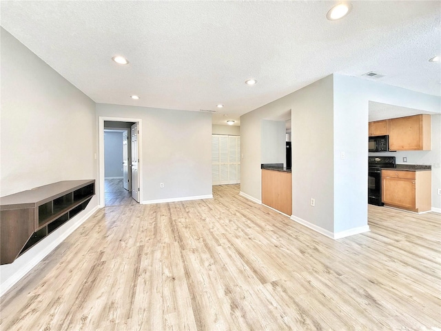 unfurnished living room with light wood-type flooring, baseboards, visible vents, and a textured ceiling