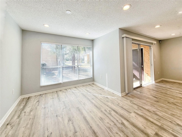 spare room with a textured ceiling, baseboards, and wood finished floors