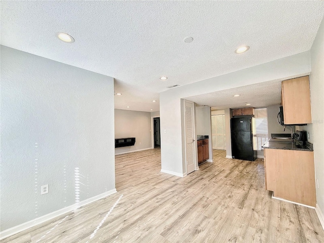 kitchen featuring baseboards, dark countertops, open floor plan, freestanding refrigerator, and light wood-type flooring