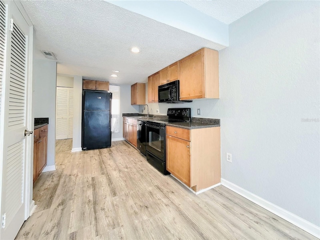 kitchen featuring dark countertops, visible vents, a textured ceiling, and black appliances