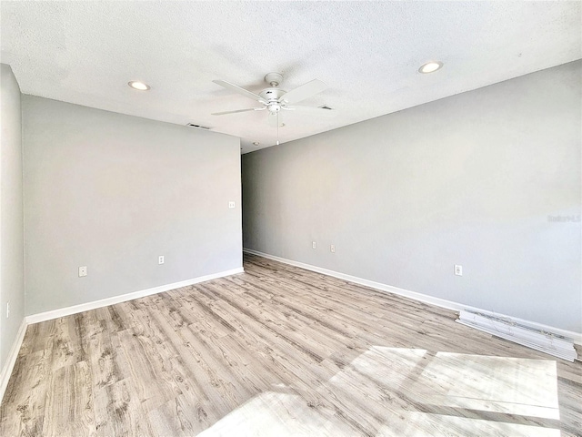 spare room with light wood-style flooring, a textured ceiling, baseboards, and a ceiling fan