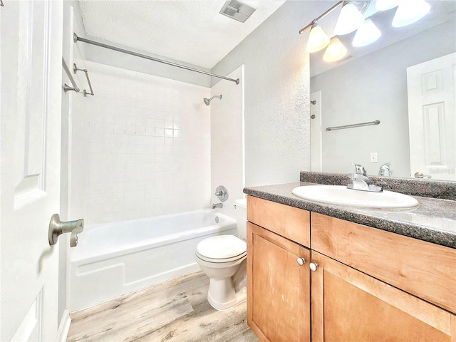 full bath featuring a textured ceiling, toilet, wood finished floors, vanity, and visible vents