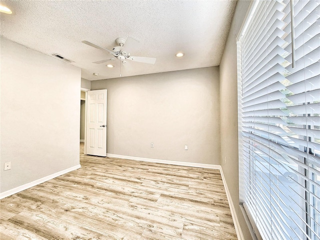 unfurnished room with baseboards, visible vents, a ceiling fan, wood finished floors, and a textured ceiling