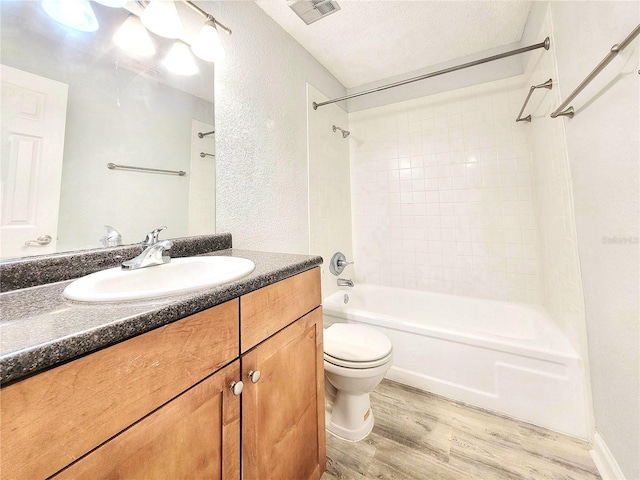 bathroom with visible vents, toilet, wood finished floors,  shower combination, and a textured ceiling