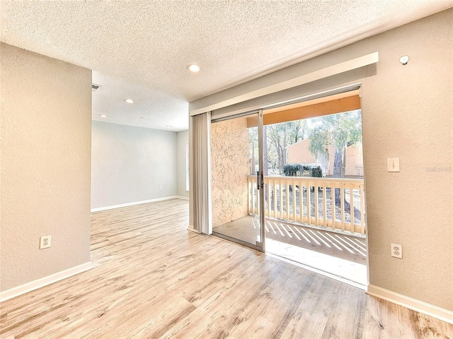 unfurnished room featuring a textured ceiling, baseboards, wood finished floors, and a textured wall