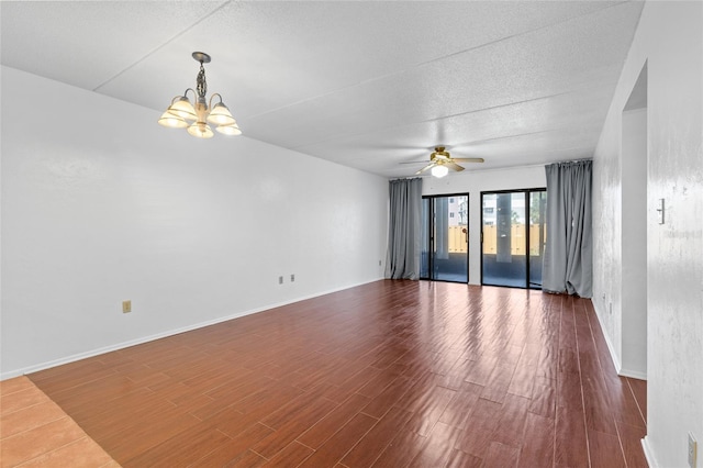 spare room with ceiling fan with notable chandelier, a textured ceiling, baseboards, and wood finished floors