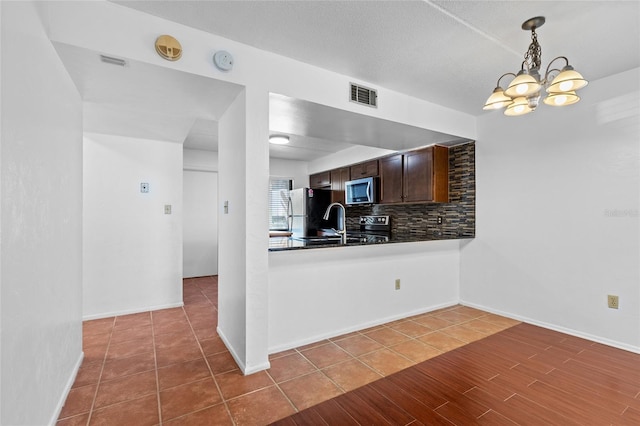 kitchen featuring visible vents, dark brown cabinets, appliances with stainless steel finishes, tasteful backsplash, and dark countertops