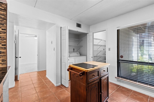 kitchen with light tile patterned floors, visible vents, a textured ceiling, dark brown cabinets, and separate washer and dryer